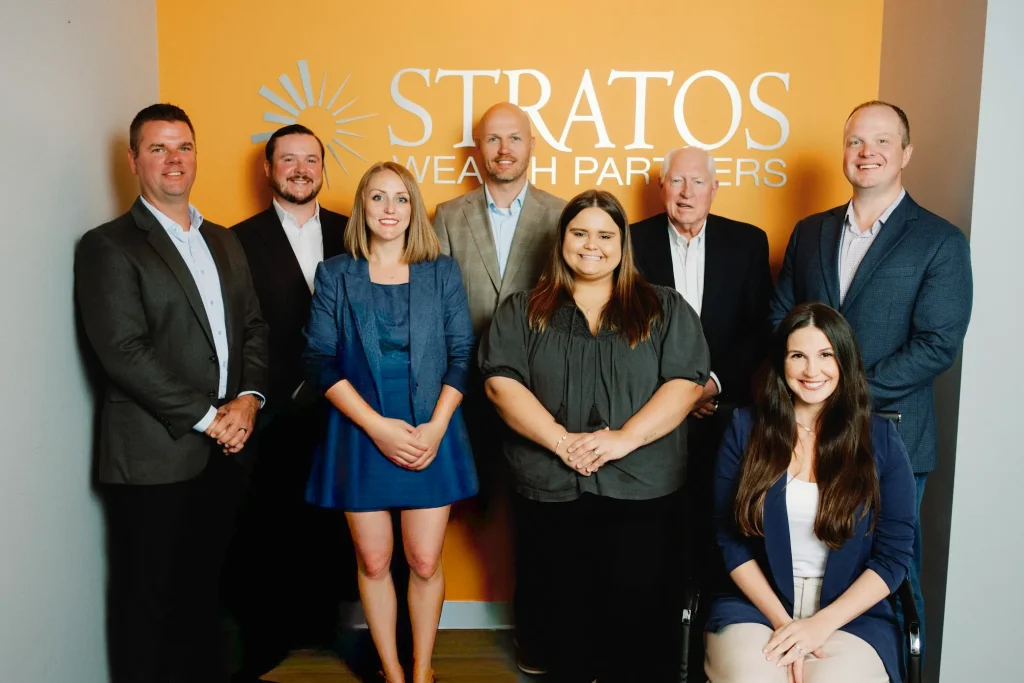 Stratos Wealth Partners, Butson Financial Advisor, LLC posing for a team photo in front of a yellow logo wall
