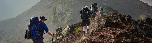 People hiking up a mountain with backpacks